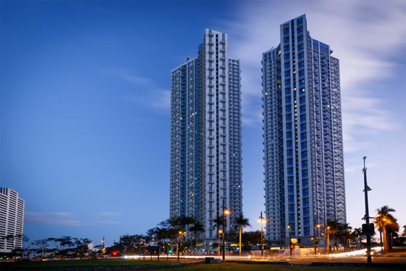 Exterior view of The Trion Towers in BGC, Taguig at dusk with city lights and clear skyline.